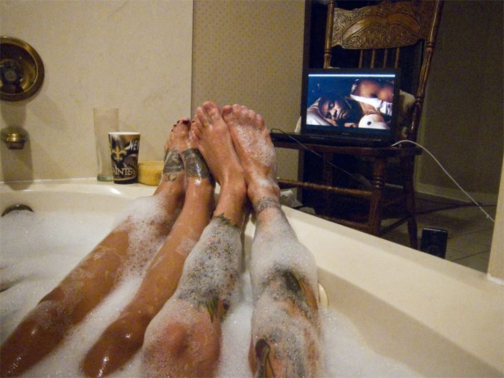 Piernas de pareja en una bañera viendo tele 