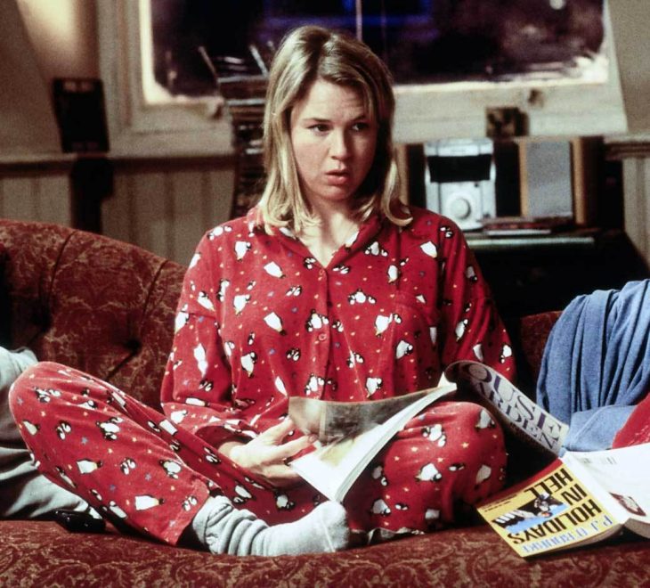 chica sentada en el sofá con pijama roja rodeada de revistas 