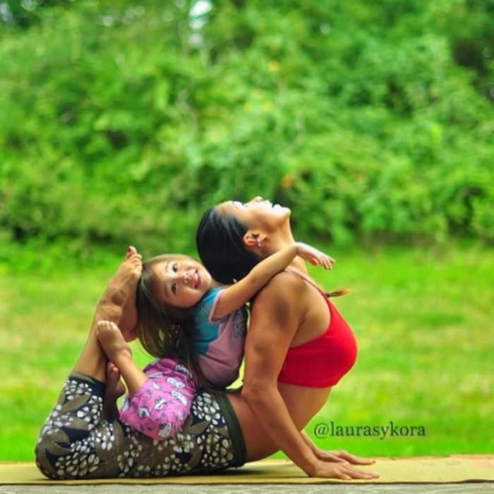 niña sobre las piernas de su madre complementando un paso hacia atrás de yoga 