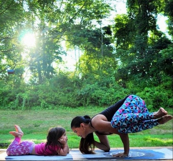 Madre e hija sobre un tapete practicando yoga 
