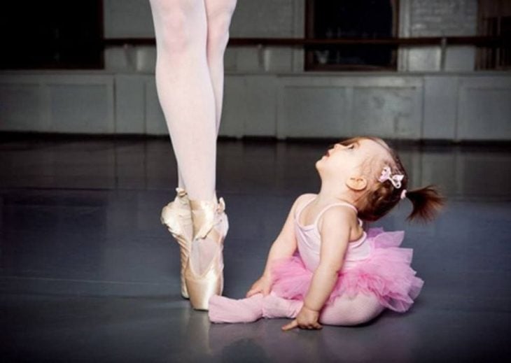 Niña vestida de ballet mirando hacia arriba viendo a su mamá 