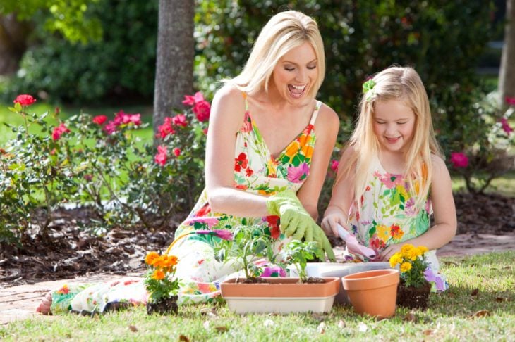 niñas y madres en un jardín arreglando las flores 