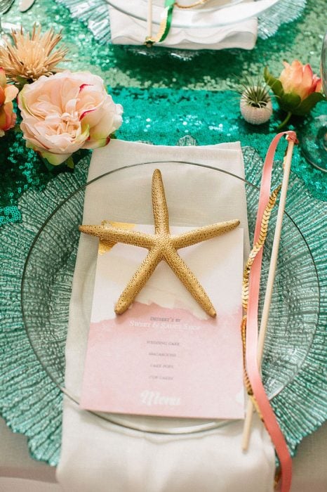 estrella de mar sobre un plato en una mesa con mantel de color verde y flores blancas 