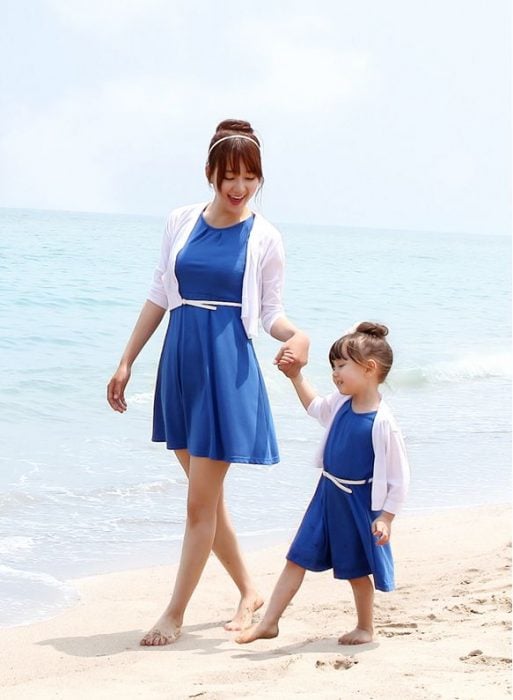 madre e hija usando el mismo vestido caminando por la playa 