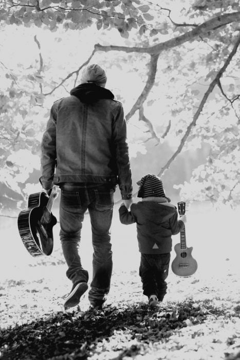 papá caminando con su hijo y una guitarra en la mano 