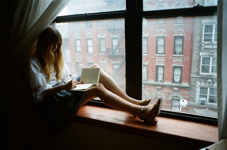 Chica en una ventana escribiendo una carta 