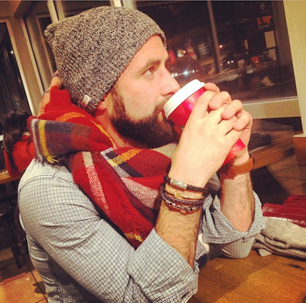 man wearing scarf and hat drinking coffee 