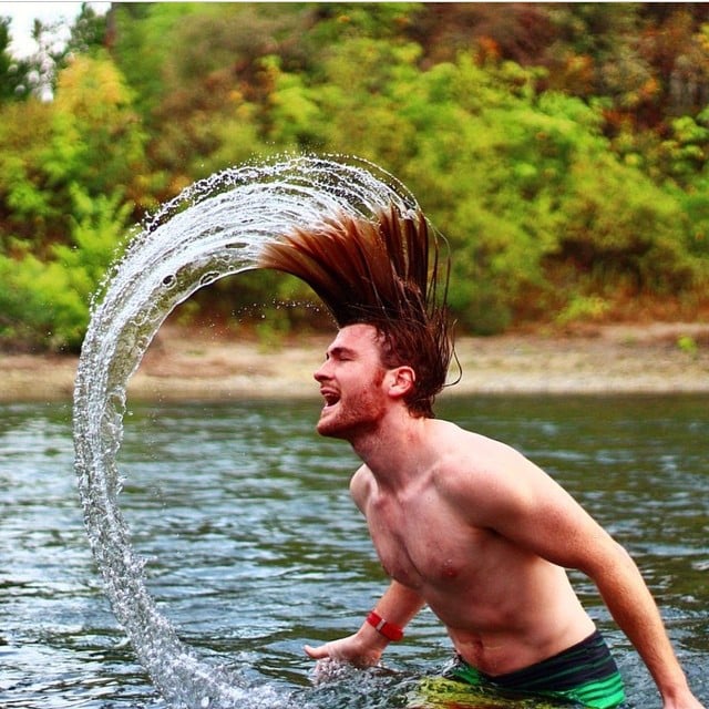 man lifting water with his hair when leaving a pond 