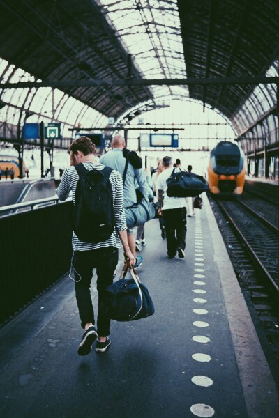 Chico con una maleta en sus manos y una mochila mientras camina por la terminal del tren 