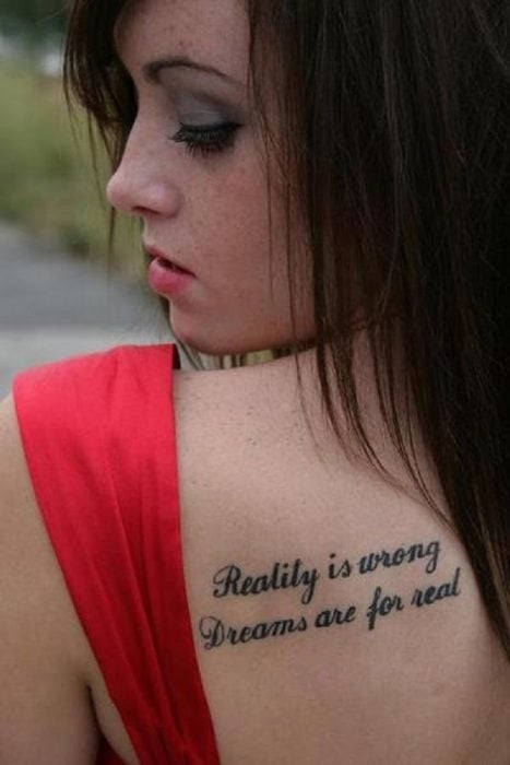 Chica vestida de rojo con un tatuaje de una frase en su espalda 