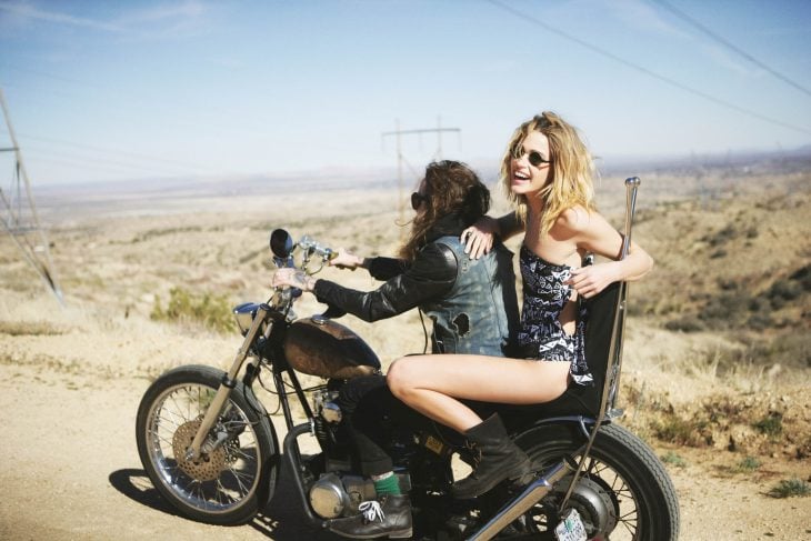 Chica en una motocicleta con un chico mientras van por la carretera 