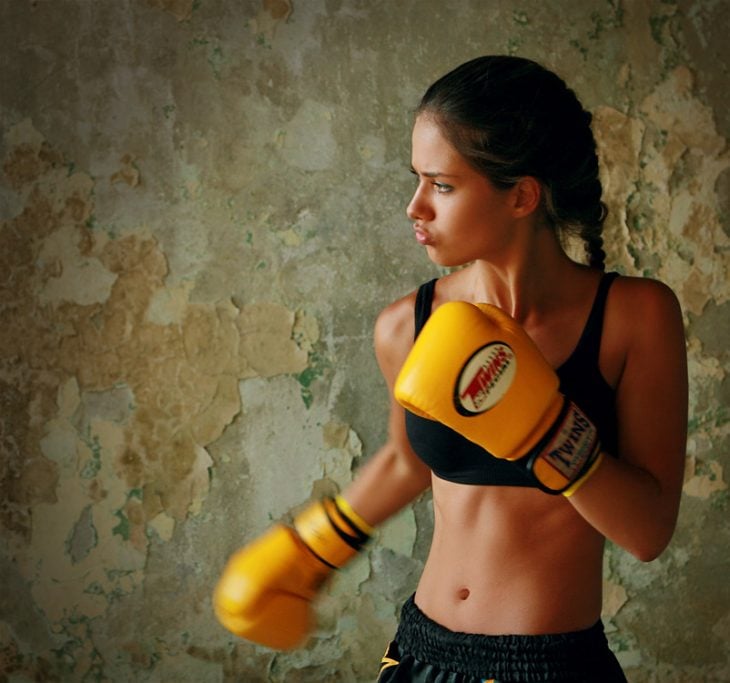 Chica usando unos guantes de box amarillos para luchar 