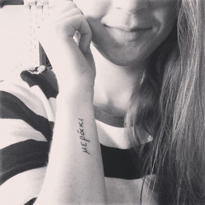 Chica con un tatuaje de la frase meraki en si brazo