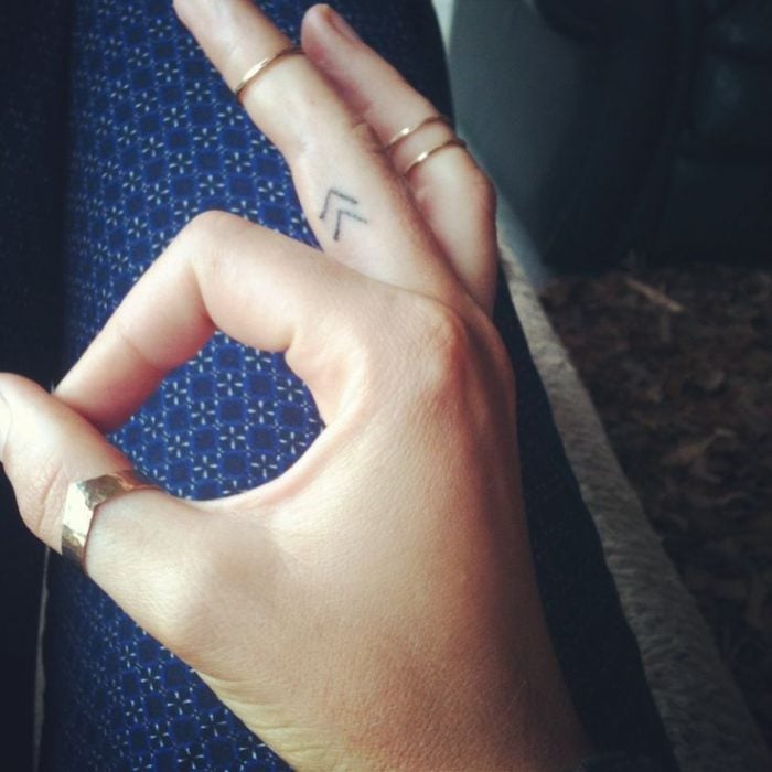 Mano de una chica con un tatuaje de lineas que parecen flechas