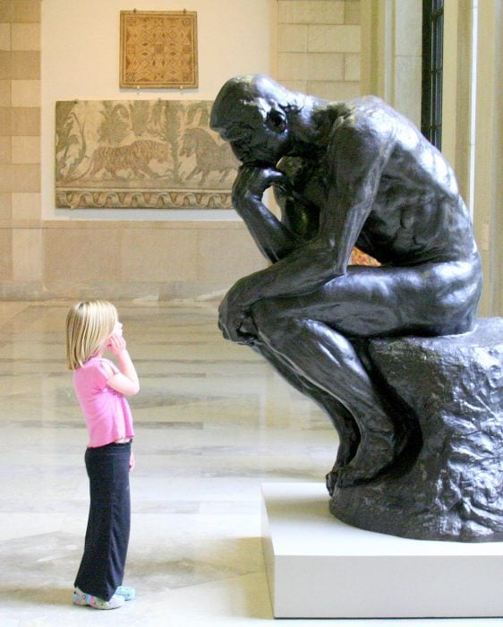 Niña mirando fijamente a una estatua