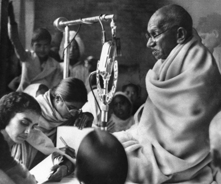 Gandhi sentado con personas escribiendo