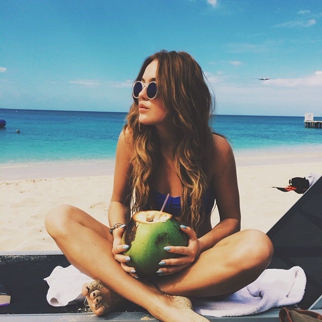Chica tomando agua de coco en la playa 