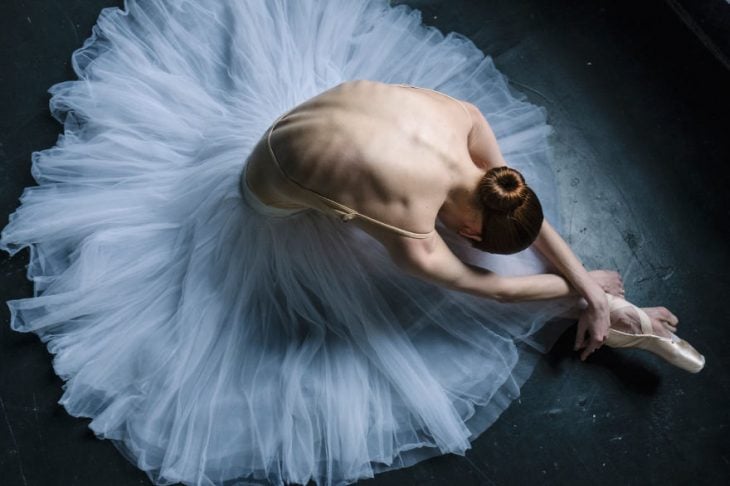 Bailarina de ballet descansando en el escenario