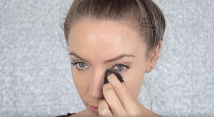 mujer rubia aplicando maquillaje en ojeras