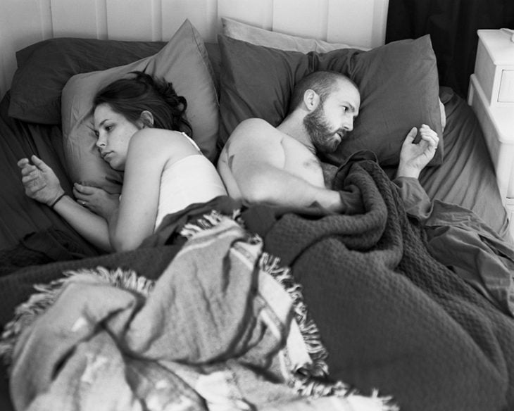 pareja de espaldas en una cama mirando sus manos 