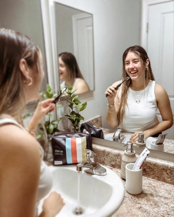 Chica frente al espejo lavando sus dientes 