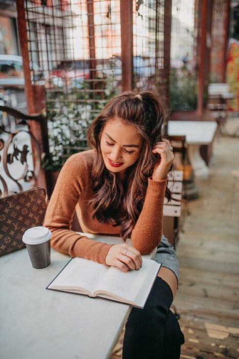 Chica en una cafetería leyendo un libro