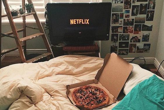 Chica mirando netflix mientras come pizza 