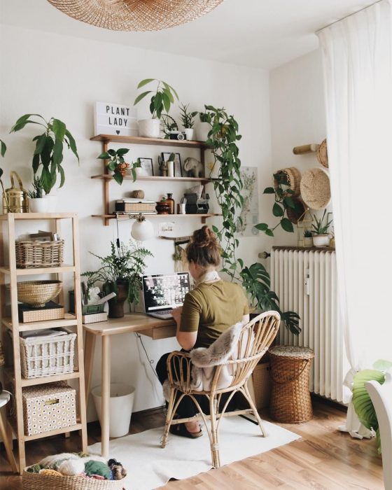 Chica en la computadora, rodeada de plantas