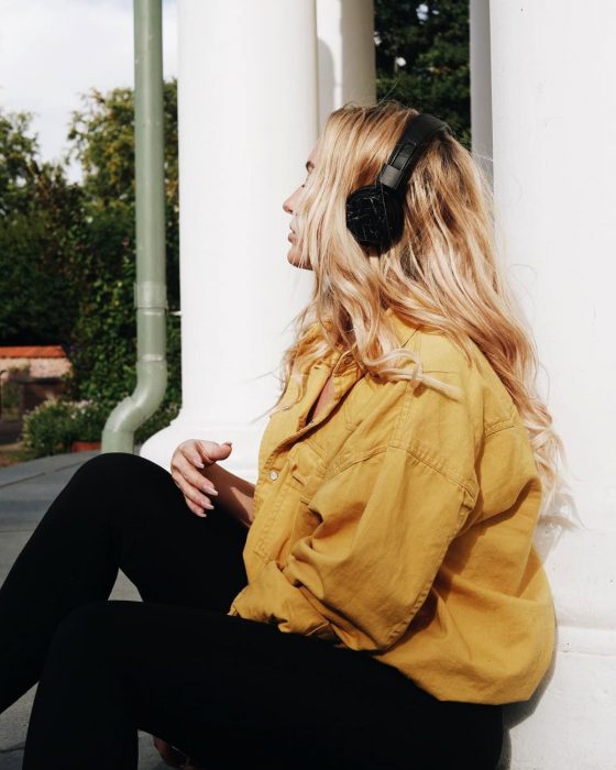 Chica de chamarra amarilla escuchando música con audífonos