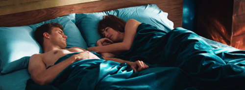 sposi sdraiati su un letto con lenzuola blu 