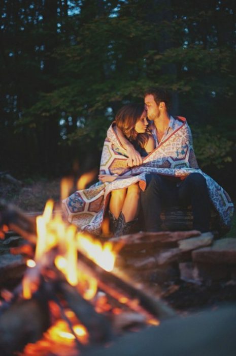 pareja abrazada frente a una fogata