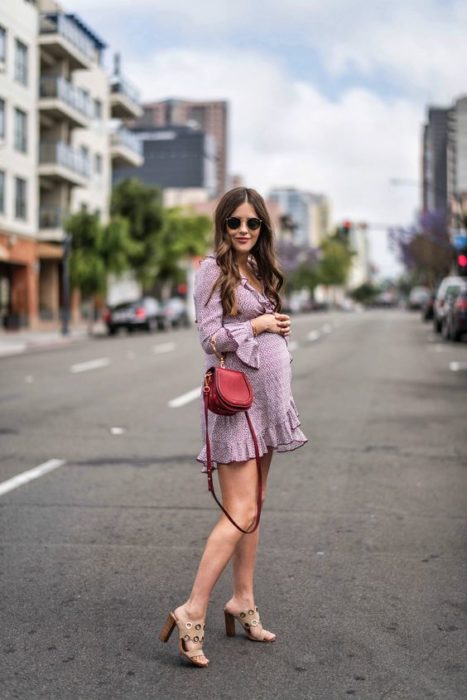 Chica embarazada con vestido morado y bolsa café