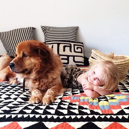 Una niña recostada en la cama con su perro 