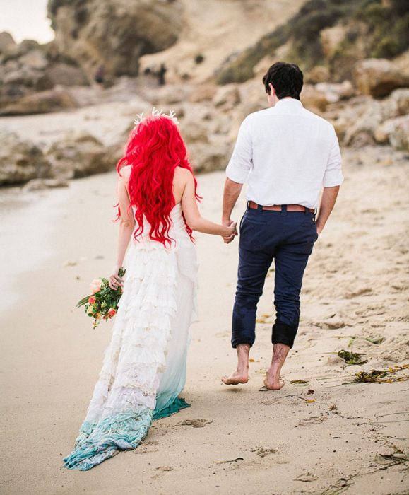 pareja de novios caminando por la playa tomados de la mano 