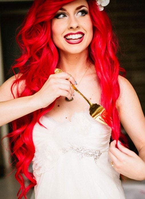 chica de cabello rojo y vestido blanco usando un tenedor para rizarse el cabello 