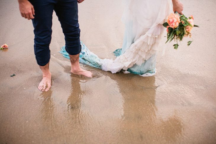 pies de unos novios parados en la playa 