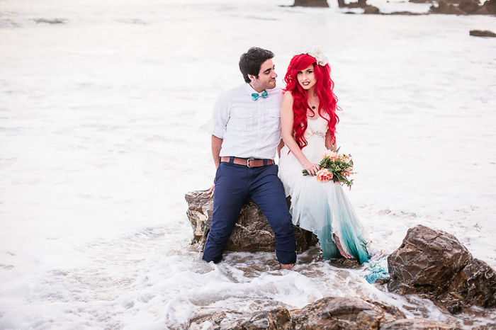 novios sentados en una roca que esta en el mar 