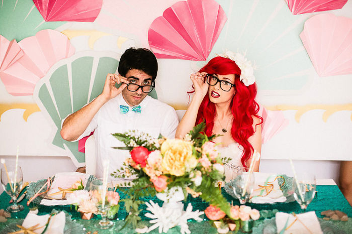 pareja sentada frente a una mesa que tiene flores mientras muestran sus lentes 