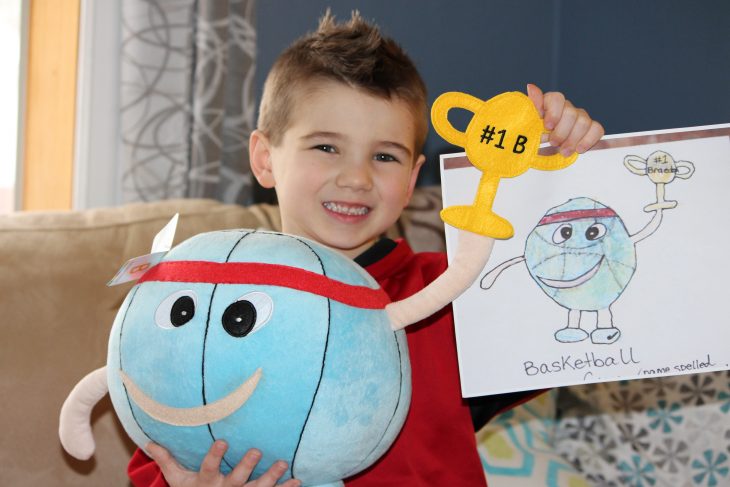 Niño con su dibujo y su peluche de un balón de basketball 