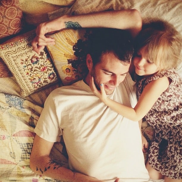 Papá e hija acostados en la cama platicando 