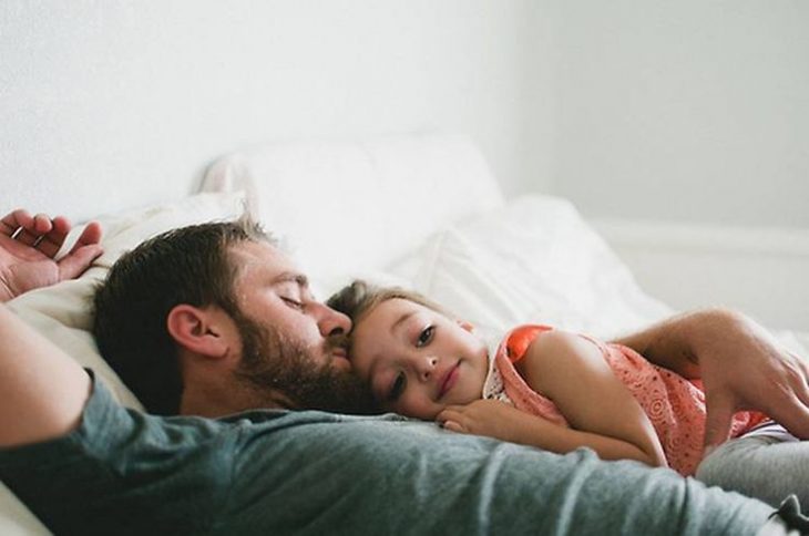 Niña pequeña acostada con su papá