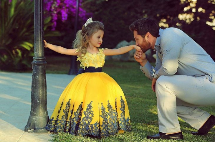 niña vestida de princesa y su papá besandole la mano 