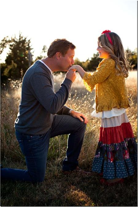 Padre besando la mano de su pequeña hija al atardecer