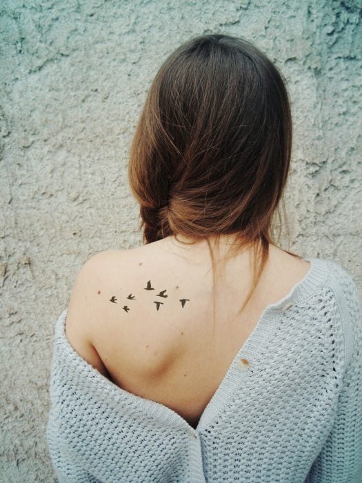 Mujer con un tatuaje de aves en la espalda 