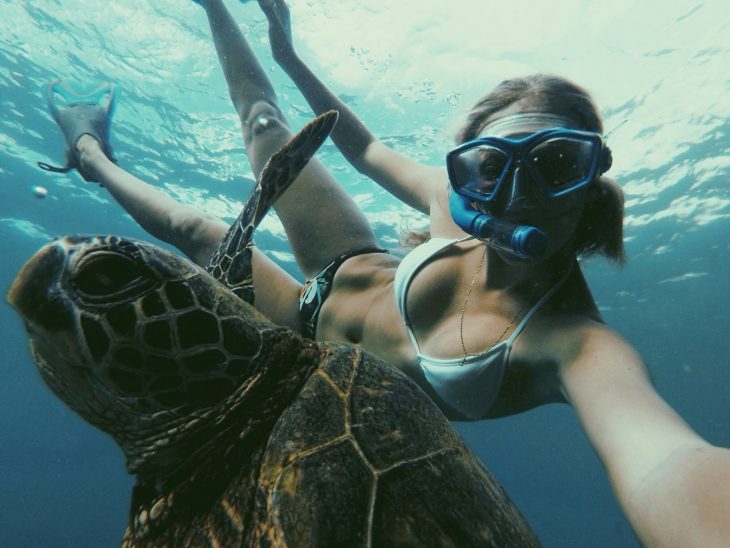 Chica practicando snorkeling con una tortuga marina 