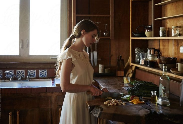 Mujer con vestido blanco cocinando en una cocina rustica 