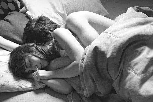 pareja de novios recostados en la cama abrazados 