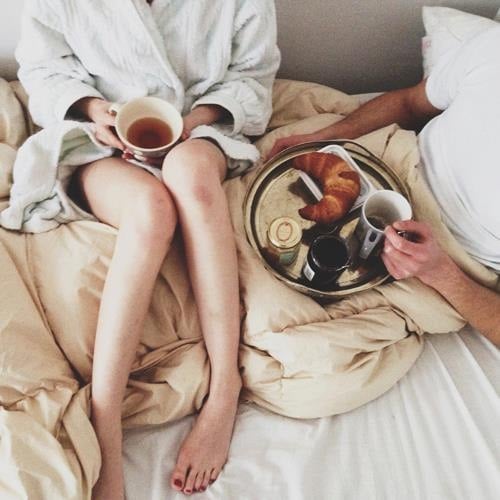 novios en la cama desayunando y tomando café