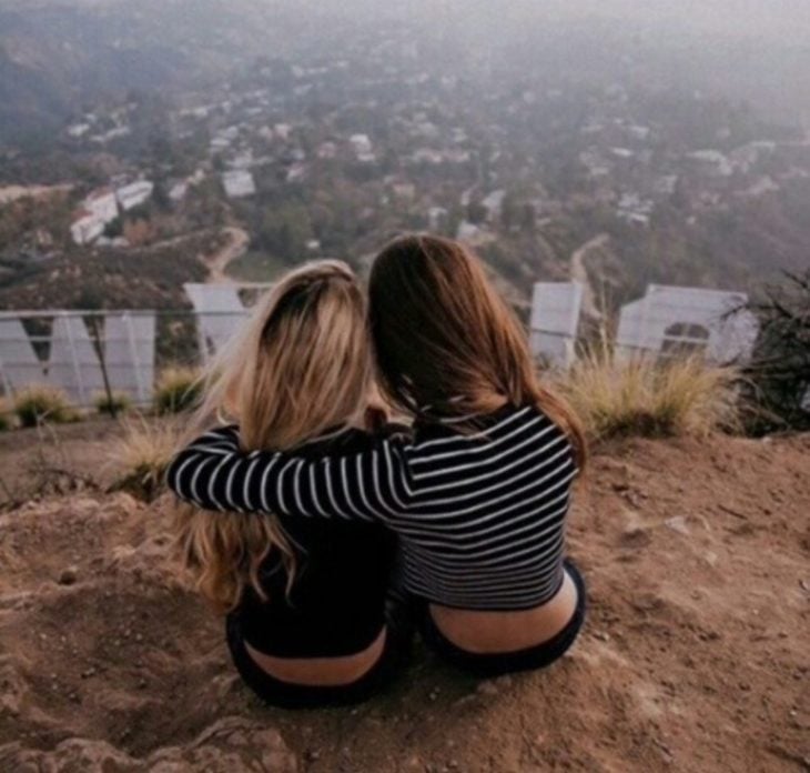 Chicas abrazándose sentadas en una colina