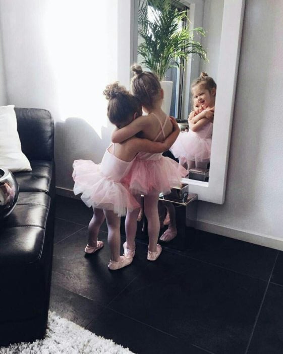 Niñas con vestido de bailarina abrazándose frente al espejo